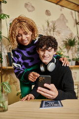 Stylish couple enjoying a cozy moment in a cafe while engaging with their smartphone together