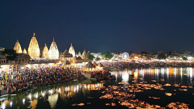Aerial view of colorful crowd at Pushkar Fair with illuminated temples and ferris wheel during twilight hours