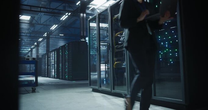 Technicians move through a modern data center, using laptop and equipment carts with hdd to inspect server racks, monitor hardware status, network operation rows of servers and organized cabling.