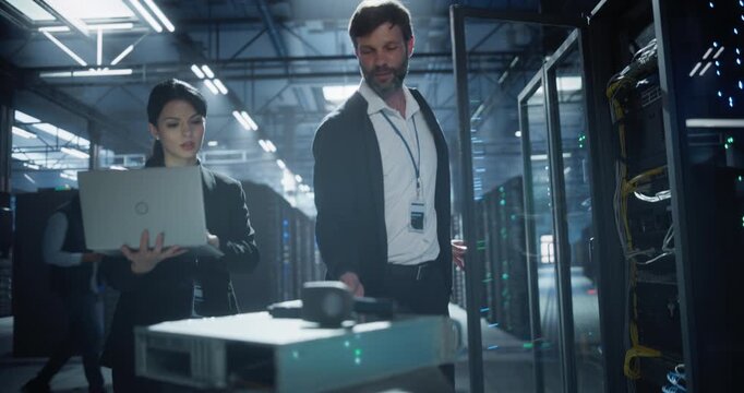 Two technician moves a cart through a data center, opens a server rack, and inspects network hardware among rows of servers, equipment maintenance, cable management, and system reliability in a secure