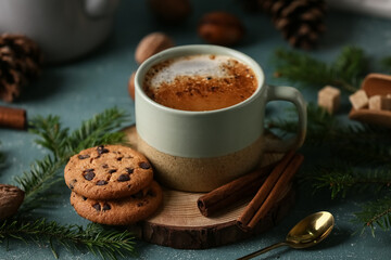Cup of coffee with cookies, spoon and winter decor on blue grunge background, closeup