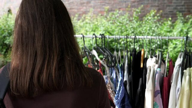 A woman browsing clothes at a flea market, embracing conscious consumption and sustainable fashion