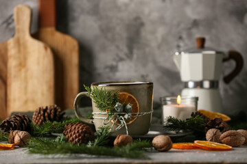Cup of hot chocolate with candle and winter decor on grey grunge background