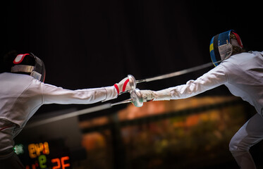 Two female fencing athletes fighting
