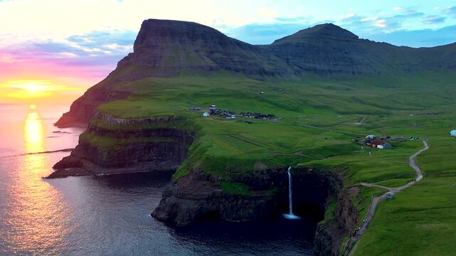 Explore the breathtaking beauty of Mulafossur waterfall cascading into the ocean, surrounded by the picturesque Gasadalur village.
