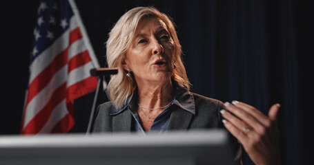 Politician, speaker and woman with American flag on a stage for election, debate or voting campaign. Government, candidate and mature person for press conference, political rally and speech by podium