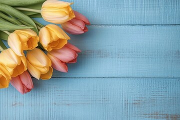 A bouquet of yellow and pink tulips placed on a blue wooden surface evoking a fresh and cheerful springtime mood