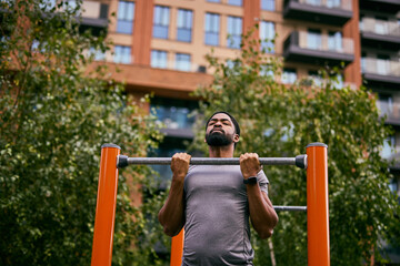 Obraz premium Athletic Man Performs Pull-Up At Outdoor Gym In Urban City Setting