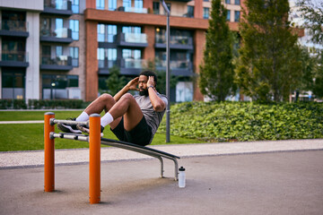 Man Performing Ab Workout on Outdoor Fitness Equipment in Modern Urban Park Setting