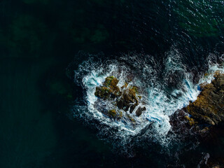 Waves crashing against rugged rocks create a mesmerizing display of nature's fury at the coast during late afternoon light