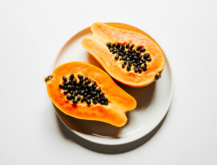 Freshly cut papaya halves with black seeds on a white plate