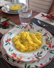 Table setting with bright tableware, berries, and twigs. Saffron risotto on plate. Traditional Italian food. Aesthetics and lifestyle. Interior design. 