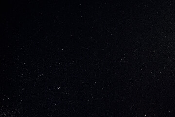 Dark granular surface enriched with glitter and golden inclusions, sharp macro focus highlights rare spark points