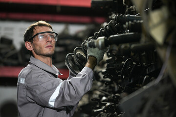 White man technician examines used car damaged engine block at scrap yard warehouse recycle area...
