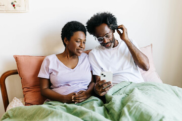 Married couple enjoying social media and technology in their bedroom