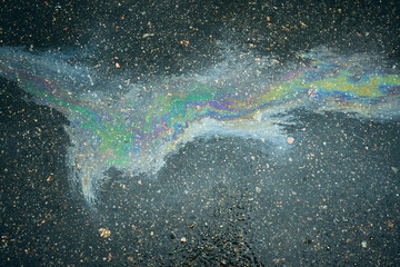 Oil refracting light on wet asphalt, creating a vibrant, rainbow-colored stain