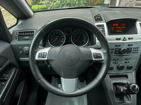 Inside view of a modern car's dashboard with sleek design and controls, capturing the essence of driving in an urban landscape during a bright day