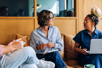 Colleagues discussing ideas on a sofa in a cozy office environment