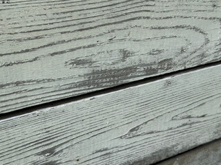 Rustic weathered wooden structure with peeling paint. Aged wooden wall in natural light. Close-up of an old wooden surface painted with light paint and featuring a natural wood grain pattern. 