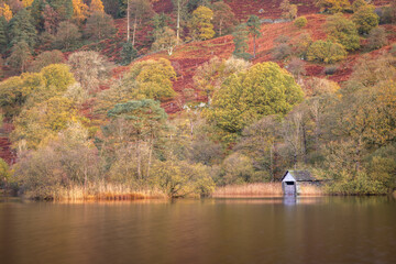 A boathouse on Rydal Water in the Lake District, Cumbria, England, in autumn, surrounded by autumnal colours