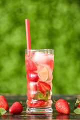 Glass of strawberry lemonade on wooden table outdoors