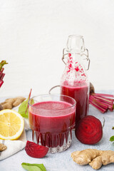 Bottle and glass of fresh beetroot juice with ingredients on light background