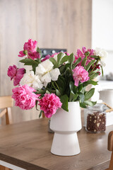 Vase with beautiful peony flowers on table in modern kitchen