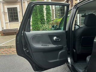 Car door swings open to reveal a quiet outdoor space with lush greenery and brick pathways, inviting exploration on a serene day