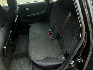 Backseat of a compact car showcases spacious yet cozy seating for three passengers during a rainy...