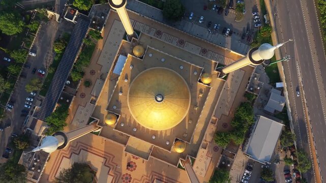 Aerial view of the National Mosque's golden dome and minarets amid geometric patterns, lush trees, and roads, Abuja, Federal Capital Territory, Nigeria.