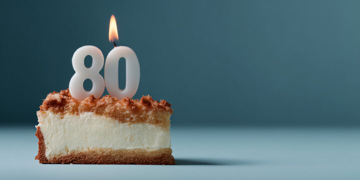 A delicious piece of cake with a lit candle, representing the number 80, on a teal background. The soft glow of the candle symbolizes a milestone celebration