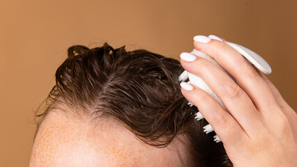 Naklejka premium Scalp exfoliation with massage brush and foam during washing process. Concept of trichology, scalp therapy, eco-cosmetics, and wellness haircare routine.
