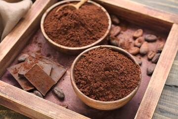 Bowls with cocoa powder, beans and chocolate on table