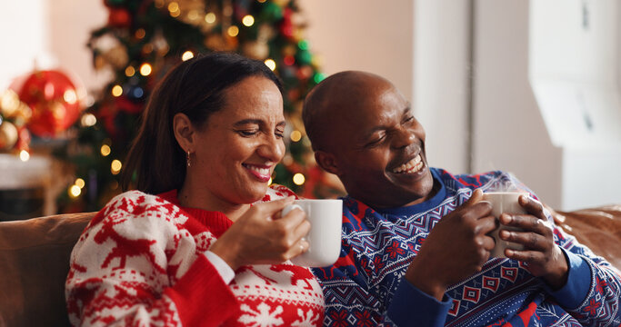 Coffee, christmas and couple on sofa in home with bonding, connection or marriage in living room. Happy, love and man with woman for drinking eggnog for festive weekend with xmas tradition in house.