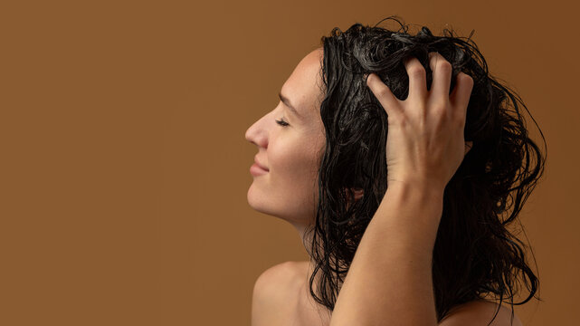 Woman massaging wet scalp with fingers during gentle hair washing. Concept of scalp wellness, trichology, self-care, and natural health routine emphasizing sensory relaxation.