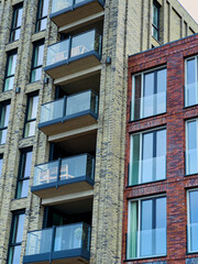 Modern architectural designs featuring brick and glass balconies in a vibrant urban setting under clear blue sky