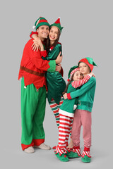 Happy family in elf's costumes hugging on grey background