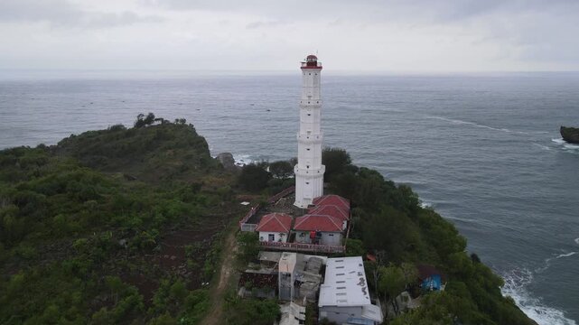 Aerial view of the Baron lighthouse stands tall against the muted tones of the sea and sky, a beacon of hope amidst the cloudy horizon, Yogyakarta, Indonesia.