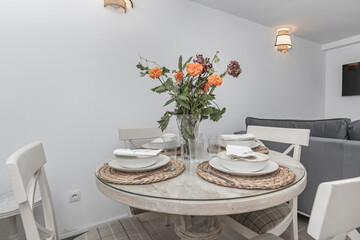  Round maple table with natural grain and armchairs, with a spring bouquet of multicolored tulips in a low vase