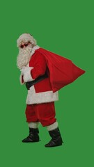 Santa Claus with a white curly beard, wearing a red suit and sunglasses, with a bag of gifts on a green background. Perfect for Christmas themed compositions, advertising, and holiday layouts.
