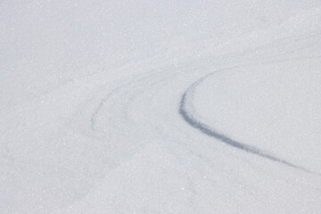 Curved lines in flat surface of fresh white snow