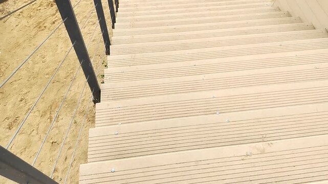 Wooden stairs to sandy beach with cable railing. Descent to sandy beach