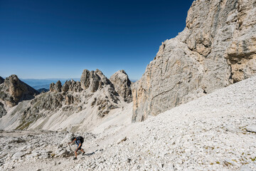 Hiker in the South Tyrolean Dolomites, Rosengarten, Italy, exploring alpine trails with dramatic mountain scenery © ikoon