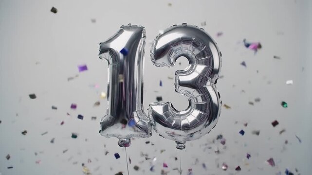Silver balloon number 13 for birthday or anniversary party. White background with falling confetti