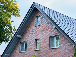 Elegant brick house with modern windows under a clear sky in a peaceful neighborhood, showcasing architectural beauty and thoughtful design details