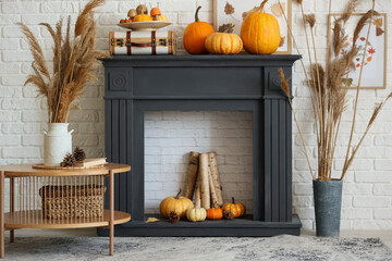 Fototapeta premium Stylish living room with fireplace, coffee table, vase of pampas grass and pumpkins. Autumn concept