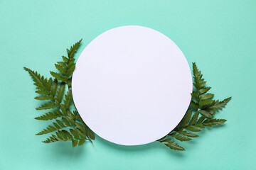 Blank card with fresh green leaves on turquoise background