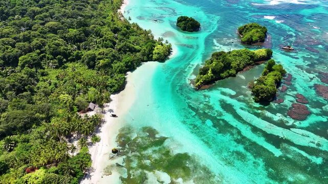 Aerial view of vibrant turquoise ocean meeting lush green tropical islands and reefs, contrasting with the white sandy beach, Bocas del Toro, Panama.