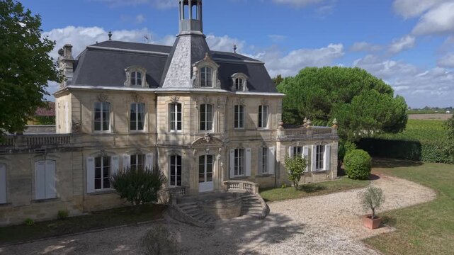 Chateau Fonreaud, France - 04 September 2025: Aerial view of a grand chateau nestled amidst lush greenery, with its elegant architecture under a bright blue sky.