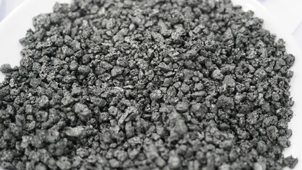 Dark gray granular material crushed minerals or industrial abrasive grains.